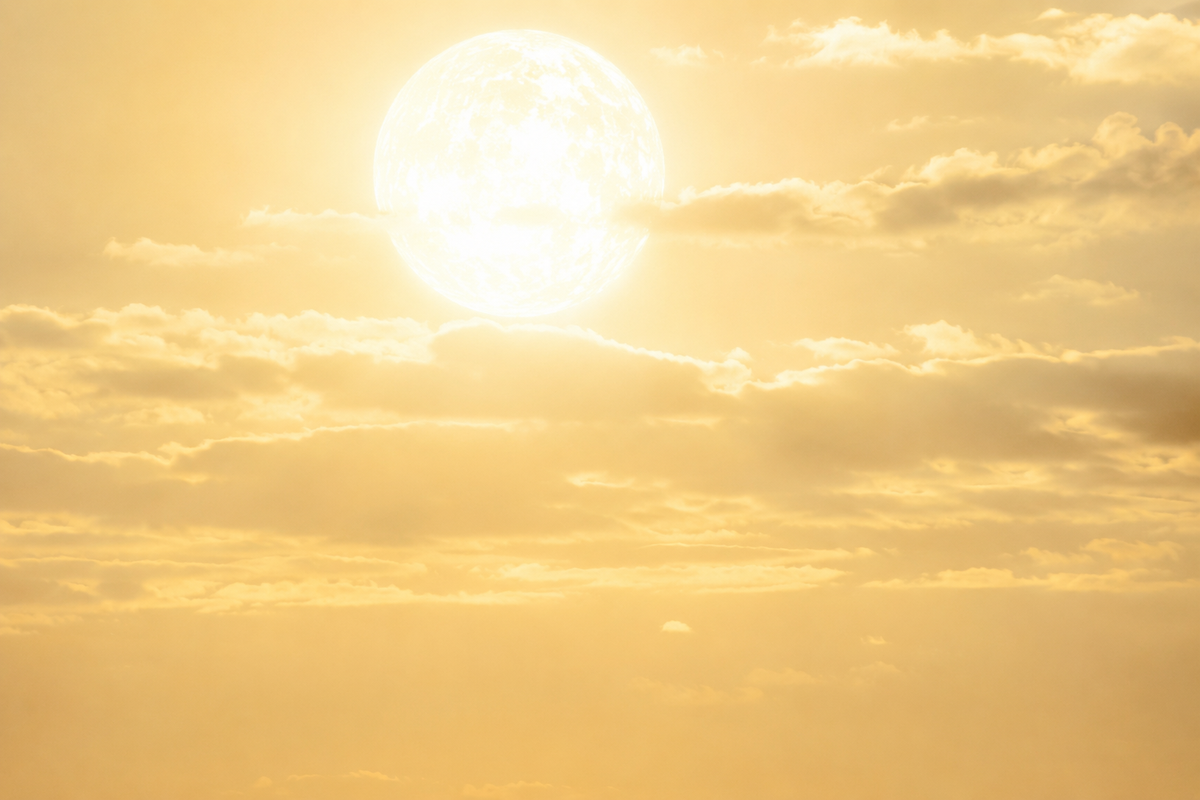 A huge white-hot sun blazing in a pale, heat-hazed sky, radiating intense ultraviolet light